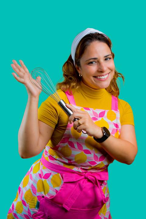 Expressão de alegria de Renata Mendes ao interagir com seus produtos, focando na paixão pela confeitaria artesanal. Foto por Bruno Arita.'