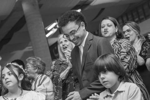 Filho do casal sorrindo em momento descontraído durante a celebração da dança. Fotografia PB por Bruno Arita.'