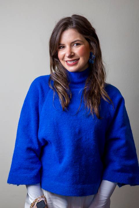 Fotografia de marketing médico com doutora sorrindo, vestindo blusa de gola alta azul vibrante e relógio inteligente, por Bruno Arita. Imagem de autoridade para a SCOPO MetLife no Centro de Convenções Rebouças.'