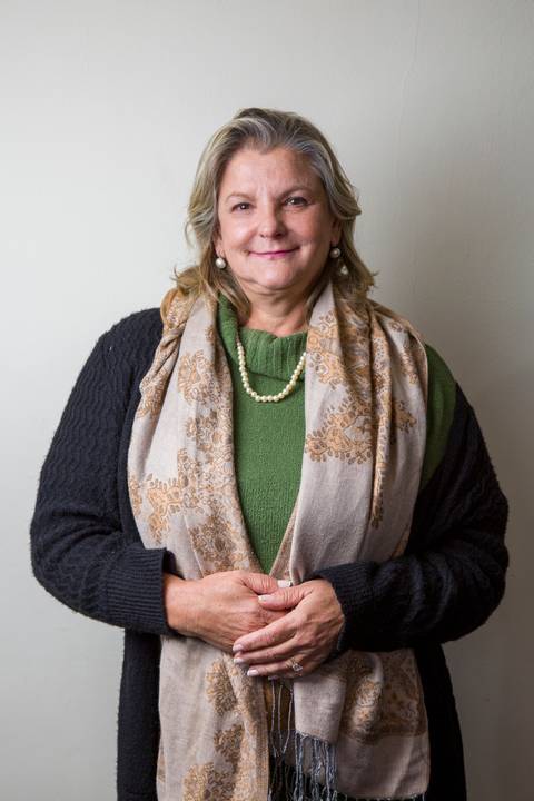 Retrato de médica sênior com colar de pérolas, echarpe estampada clara e blusa verde, transmitindo elegância por Bruno Arita. Foto de estúdio corporativo para a SCOPO MetLife no Centro de Convenções Rebouças.'