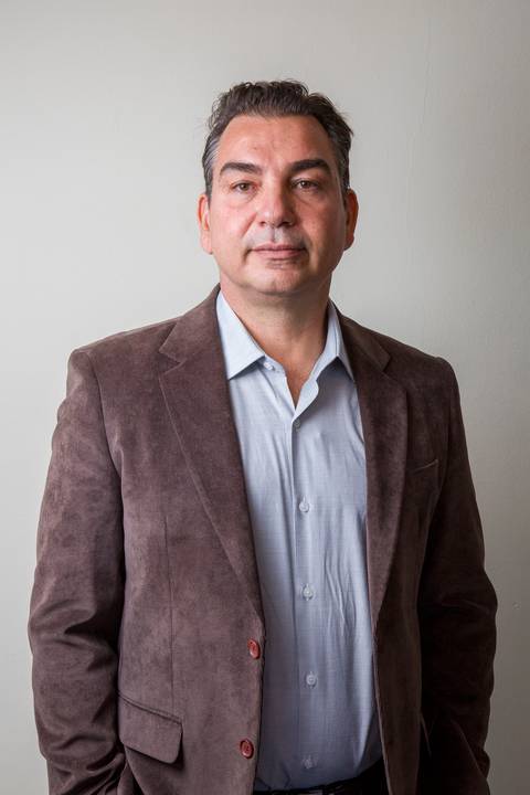 Retrato corporativo masculino de médico com blazer de veludo cotelê marrom e camisa social azul, com postura séria por Bruno Arita. Posicionamento profissional da SCOPO MetLife no Centro de Convenções Rebouças.'