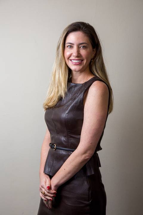 Retrato de perfil de médica sorrindo, usando vestido de couro marrom escuro acinturado, clicada por Bruno Arita. Fotografia de posicionamento de imagem e marketing médico para a SCOPO MetLife no Rebouças.'