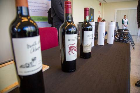Garrafas de vinho tinto e garrafas térmicas personalizadas da MetLife dispostas em mesa de recepção. Foto de cobertura por Bruno Arita no Centro de Convenções Rebouças.'