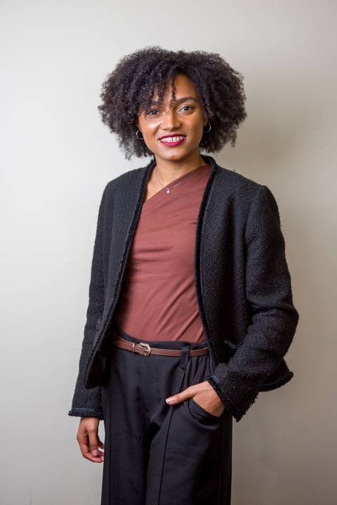 Posicionamento de imagem de médica negra com cabelos cacheados volumosos, usando blazer preto e blusa marrom, por Bruno Arita. Retrato de estúdio corporativo para a SCOPO MetLife no Centro de Convenções Rebouças.'