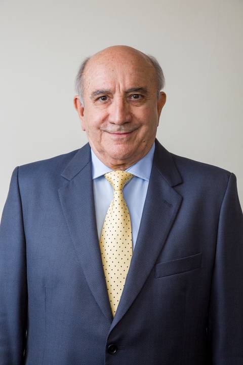 Médico sênior sorridente vestindo terno cinza escuro, camisa azul clara e gravata amarela com poá. Fotografia corporativa por Bruno Arita na ativação da SCOPO MetLife no Centro de Convenções Rebouças.'