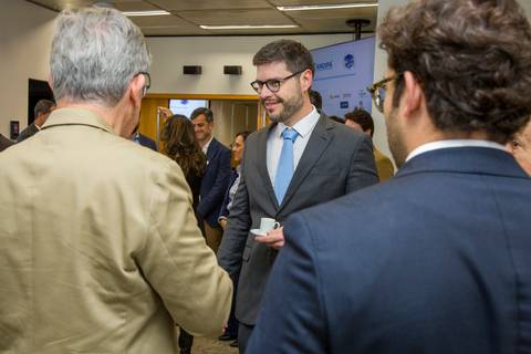 Convidados alinhados conversando com xícaras de café no foyer da FIESP durante o evento da ANDIPA. Registro espontâneo por Bruno Arita.'