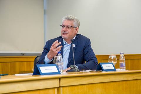 Membro da mesa gesticulando ao perguntar para palestrande durante painel na FIESP. Fotografia corporativa por Bruno Arita.'