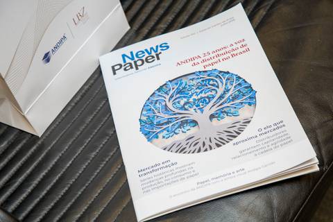 Exemplar do informativo NewsPaper com matéria especial dos 25 anos da ANDIPA sobre a mesa. Fotografia de detalhes por Bruno Arita.'