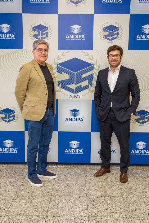 Executivos posando em frente ao painel de fotos dos 25 anos da ANDIPA na FIESP em São Paulo. Foto de posicionamento por Bruno Arita.'