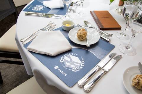 Mesa posta para o almoço comemorativo com menu e porta-guardanapo personalizado da ANDIPA. Registro de detalhes por Bruno Arita.'