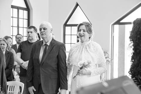 Noivos em pé no altar diante do padre durante as orações da cerimônia de casamento. Foto por Bruno Arita.'