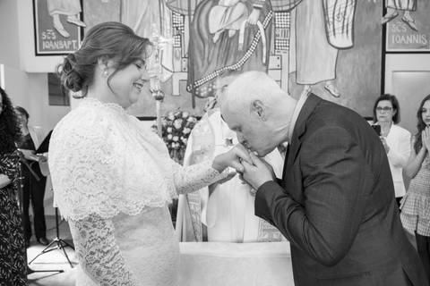Noivo Antonio Carlos beijando carinhosamente a mão da noiva Ana Paula no altar. Foto poética por Bruno Arita.'