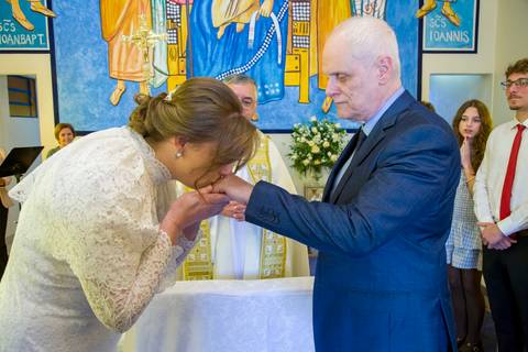 Noiva beijando com respeito e devoção a mão do noivo durante a cerimônia na igreja. Foto por Bruno Arita.'