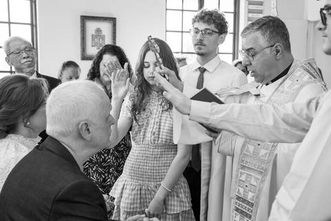 Mãos da família estendidas sobre a jovem em momento profundo de emoção e fé. Foto por Bruno Arita.'