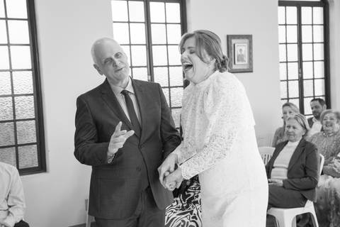 Noivos sorrindo e celebrando descontraídos no altar após o fim da cerimônia religiosa. Foto por Bruno Arita.'