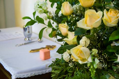Arranjo de flores amarelas e brancas sobre a mesa do altar com detalhe do terço na Capela Santa Suzana. Foto por Bruno Arita.'