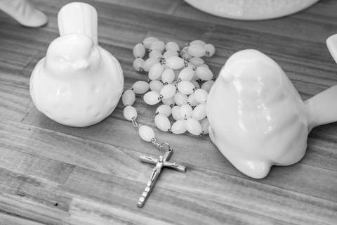 Detalhe de terço de pérolas e pequenos pássaros de louça decorativos na mesa do receptivo. Foto por Bruno Arita.'