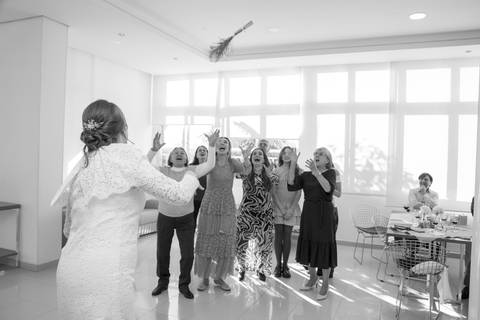 Convidadas com mãos erguidas no ar tentando pegar o buquê lançado pela noiva. Foto por Bruno Arita.'