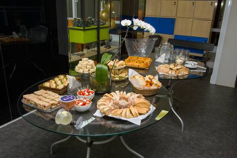 Mesa de recepção do evento com buffet de salgados, pães e sucos para os convidados. Foto por Bruno Arita.'
