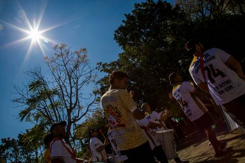 Vista em contra-luz da bateria da Prova de Fogo de Pirituba caminhando sob o sol forte e céu azul. Foto por Bruno Arita.'