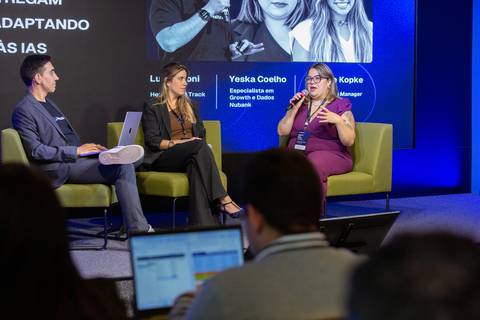 Executiva no Painel de IA: Palestrante discursando sobre métricas e adaptação de conteúdo para IAs em São Paulo. Foto por Bruno Arita.'