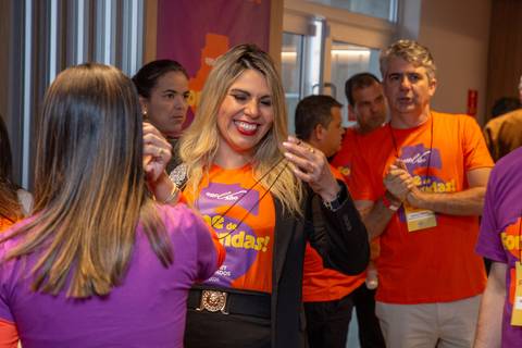 Interação no Credenciamento: Colaboradores vestidos com a camiseta laranja do evento conversando no lounge. Foto por Bruno Arita.'