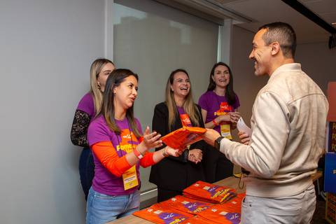 Entrega de Material: Organizadoras entregando pastas e blocos para convidado na recepção. Foto por Bruno Arita.'