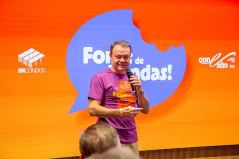 Apresentação Temática Fome de Vendas: Palestrante no palco com a identidade visual roxa e laranja do Summit BRCondos. Foto por Bruno Arita.'