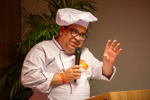 Palestrante caracterizado com dólmã de chef de cozinha falando ao microfone no Summit BRCondos. Foto: Bruno Arita.'