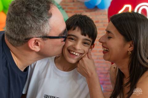 Beijo dos pais no aniversariante, em um momento de amor'