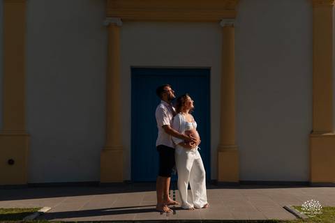 Casal abraçados em frente à arquitetura histórica, celebrando a espera da Ayla'