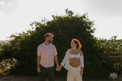 Casal caminhando de mãos dadas em meio à vegetação'