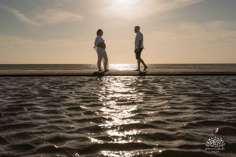 Silhueta do casal caminhando na praia ao pôr do sol'