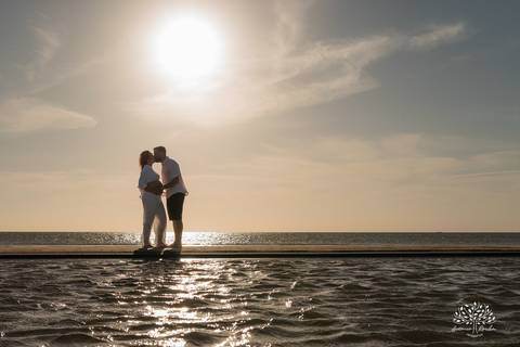Silhueta do casal caminhando na praia ao pôr do sol'