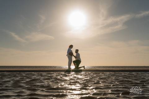 Silhueta do casal caminhando na praia ao pôr do sol'