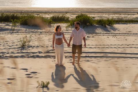 Casal caminhando entre dunas e vegetação da praia'