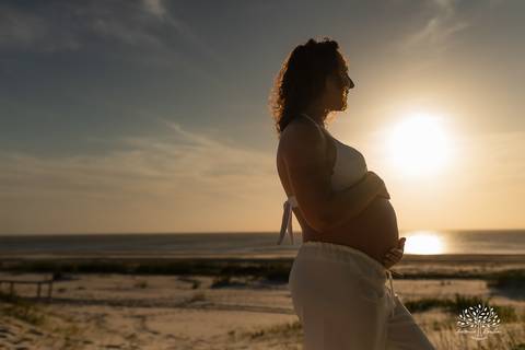 Silhueta da gestante grávida com o sol ao fundo'