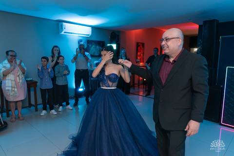 Debutante sendo conduzida pelo pai até o bolo para cantar o parabéns'