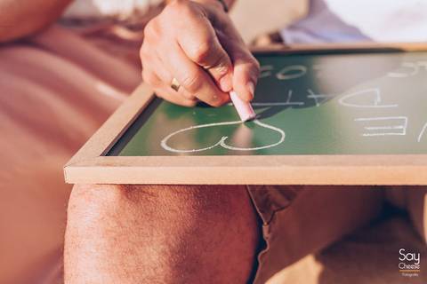 noivo desenhando em lousa de save the date em ensaio pré-wedding na praia fotografado por Say Cheese Fotografia'