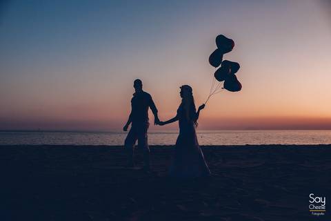 silhueta de noivos caminhando na praia com balões de coração com gás helio em ensaio pré-wedding na praia fotografado por Say Cheese Fotografia'