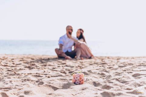 noivos sentados na areia com buque de flores em ensaio pré-wedding na praia fotografado por Say Cheese Fotografia'