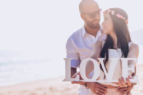 noivos segurando plaquinha com letras de mdf escrito love em ensaio pré-wedding na praia fotografado por Say Cheese Fotografia'