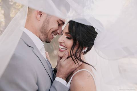 foto dos noivos dentro do véu da noiva em casamento diurno no campo em maringa'