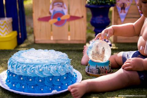 menino sentado com mãos sujas de bolo falso azul'