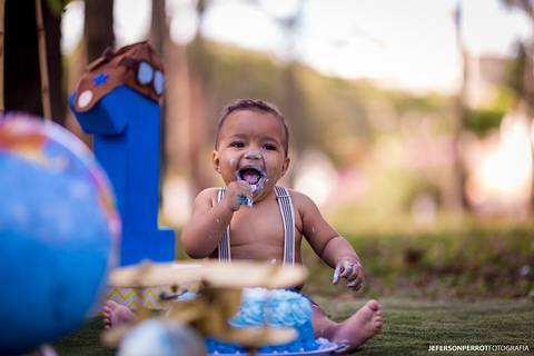 menino se divertindo e comendo bolo azul em ensaio'