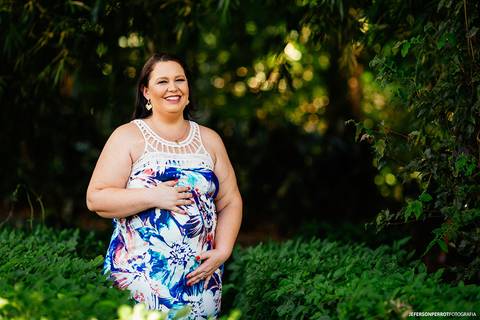 gestante sorridente em caminho natual de folhas'