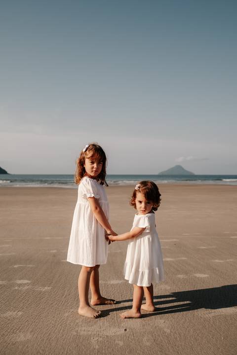 foto de ensaio familiar com irmãs olhando para trãs na beira da praia'