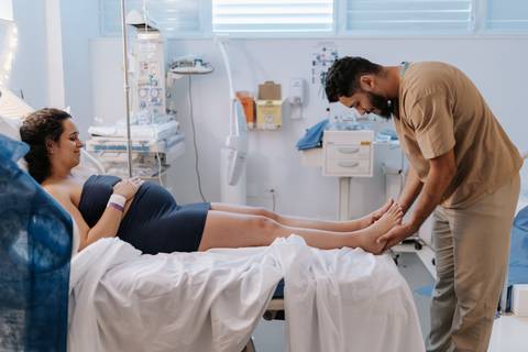 Foto do pai massageando os pés da gestante no hospital'