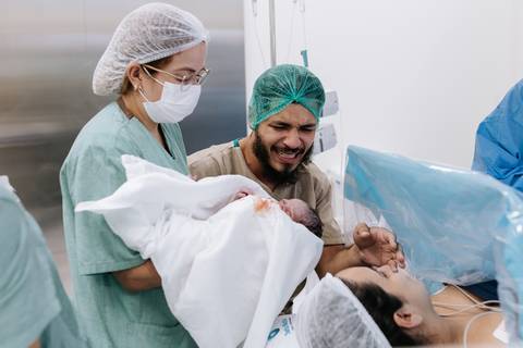 Foto da equipe apresentando o bebê para os pais'