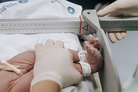Foto da medição do bebê com régua hospitalar após o nascimento'